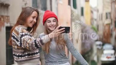 意大利，威尼斯。 两个年轻的女人站在小桥上，在一条水道的背景上<strong>自拍</strong>
