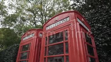 伦敦传统的红色电话亭在街上绿树掩映。 行动。 国家标志
