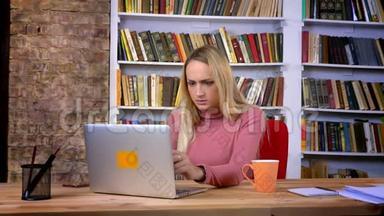 惊慌失措的白种人女孩的肖像，穿着笔记本电脑工作，在书架背景上面临麻烦。