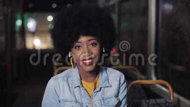非裔美国妇女看着相机，微笑着坐在公共交通工具，斯特迪卡姆拍摄。 特写镜头。 城市