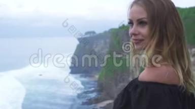 幸福的女人在海边欣赏山崖和海浪景观。 在山崖边微笑的女人