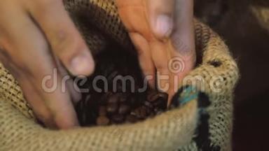 咖啡豆。 女人`手的触摸是从一袋咖啡中获取咖啡豆。 烘焙咖啡豆的品质