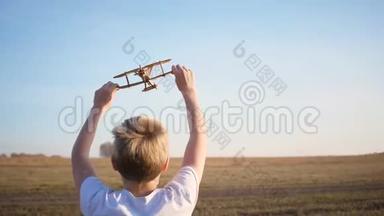 孩子跑过田野，举着飞机，模拟飞行.. 秋天晴朗的一天。 户外娱乐