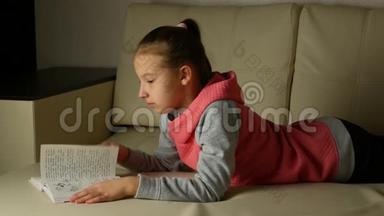 穿着灰色粉色运动衫的可爱<strong>女孩子</strong>躺在房间的沙发上看书