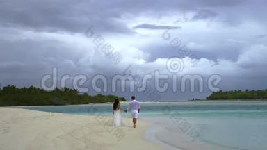 新婚夫妇手牵手在一片<strong>绚丽</strong>的白色沙滩和绿松石水上.. 背景中是一片美丽的天空.. 热带婚礼