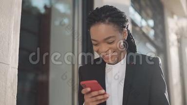 时尚的非洲女商人在户外与手机助理通话时，用手机发送音频语音信息。 商务