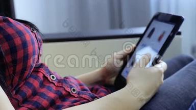 网上购物的概念。 年轻女孩坐在生活方式网上商店里看商品，用数字购物
