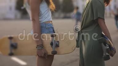 起重机射击。欧洲小镇街头阳光下玩滑板的两个少女朋友的照片