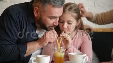 青春期的小女孩和她爸爸在咖啡馆里玩得很开心。 他们用冰块喝深红色果汁