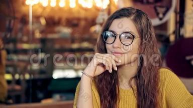一个漂亮女孩在一家带眼镜的舒适咖啡店的肖像。