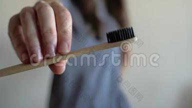 女人手上的特写显示竹制牙刷。 <strong>零废物</strong>，浴室，无塑料