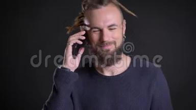 一个中年白种人，长着可怕的长发，在黑色背景下用手机讲话。