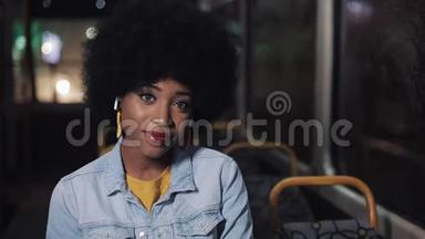 非裔美国妇女看着相机，微笑着坐在<strong>公共交通工具</strong>，斯特迪卡姆拍摄。 特写镜头。 城市