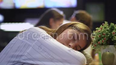 一个年轻女孩靠在咖啡馆的桌子上睡觉。 一个年轻的女孩在一家健康食品咖啡馆里睡觉