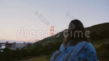 镜头跟随年轻的旅游妇女背包徒步上大山欣赏<strong>壮观</strong>的金门<strong>大桥</strong>日落景色。