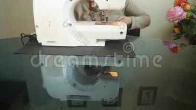 白色电动缝纫机的正面视图及其在Balck桌子上的反射。 背景白手缝制材料