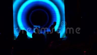 DJ在一家夜总会的迪斯科舞厅工作，背景是大屏幕。