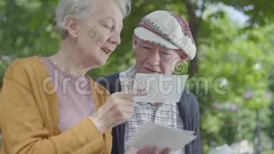 特写肖像可爱的成年夫妇看着<strong>老照片</strong>，回忆着坐在公园长凳上的快乐时刻