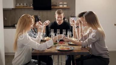 一大群亲密的朋友坐在餐桌旁，手<strong>牵着</strong>手在晚餐前祈祷。