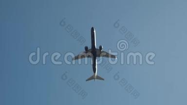 从底部看一架白色的大客机在晴朗的蓝天上飞行。 行动。 乘飞机去夏天