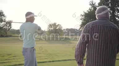 英俊的中东高尔夫球<strong>手</strong>在美丽的球场上摇摆和击球。 一个年长的人看着他的对<strong>手</strong>