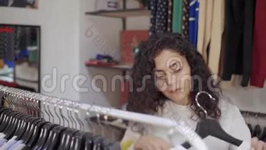 一个女人在商场的服装店买衣服，从衣架上拿衣架