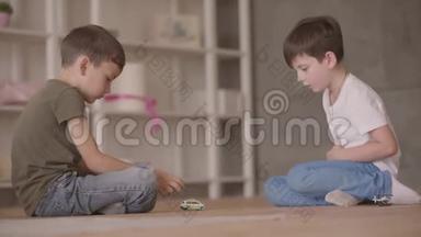 两个弟弟坐在地板上玩玩具汽车坐在地板上在家里。 小兄弟花时间