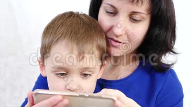 幸福的家庭：妈妈和儿子拿着智能手机，在网上玩儿童应用程序
