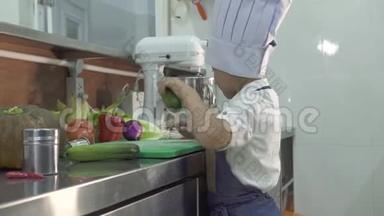 小男孩厨师穿着围裙做饭，厨师帽在餐厅厨房做饭。 有趣的小厨师切鲜菜