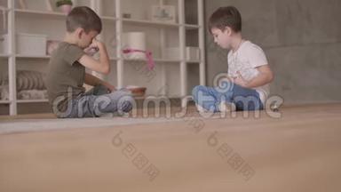 两个可爱的兄弟坐在地板上玩玩具车坐在地板上在家里。 小兄弟花时间