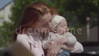 一位年轻漂亮的母亲抱着一个可爱的孩子在春天阳光明媚的日子里和他说话