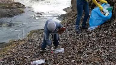 女志愿者带着她的孩子清理河边的垃圾。 生态和环境概念