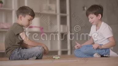 两个可爱的兄弟坐在地板上玩玩具车坐在地板上在家里。 小兄弟花时间