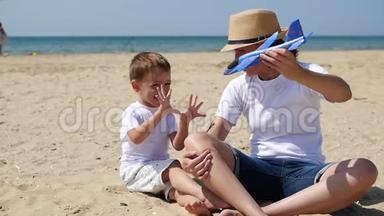 <strong>妈妈和宝宝</strong>坐在沙滩上。 女人在飞机上<strong>和</strong>一个小男孩玩。 幸福的情绪