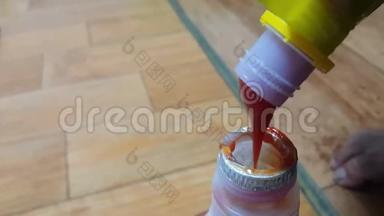 从黄色瓶子倒入小瓶子的红色番茄酱的顶部视图。
