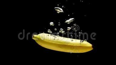 黄色香蕉在黑色背景下落入透明水