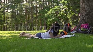 年轻的亚洲女孩躺在公园的空地上，每天写一封信
