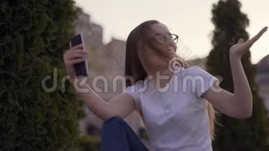 你好！ 年轻女孩正对着屏幕对着她的男朋友在春天公园打视频电话时，正对着镜头挥手