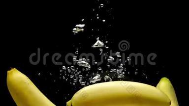 <strong>三根</strong>黄色香蕉在黑色背景下落入透明水
