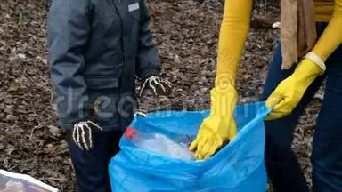 女志愿者带着她的孩子清理河边的垃圾。 生态和环境概念