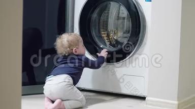一岁男孩在家看洗衣机。 家用电器问题。 小男孩打开洗衣机