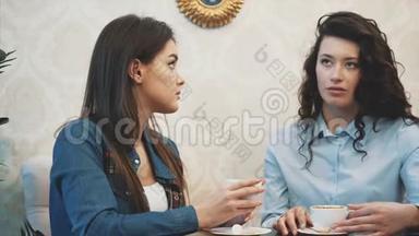 三个女孩在咖啡馆里的交流。 坐在严肃的话题上。 有幽默感和长发。