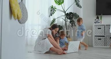 妈妈带着两个小孩坐在一间现代化公寓的地板上，明亮的房间里有一台笔记本电脑。注意