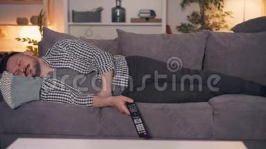 疲惫的人独自躺在沙发上拿着电视遥控器的画像