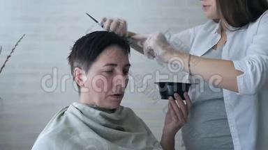 一位怀孕的美发师在一家美容院从事染发，专业染发和护发，一家美容院..