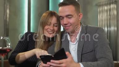 一对年轻漂亮的夫妇在咖啡馆里约会，在智能手机上看照片