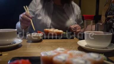 女人用木筷子吃寿司。 特写镜头。 中国筷子吃寿司卷