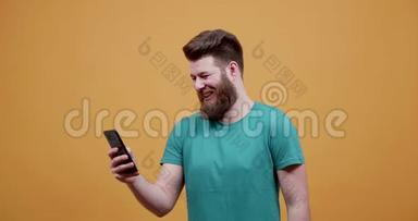 男人在黄色背景下看手机上的有趣图片和视频