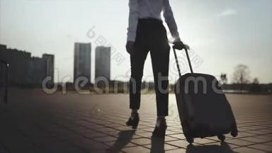 商务女士带着行李从机场去出租车停车场。 穿高跟鞋的女孩踩着<strong>行李箱</strong>