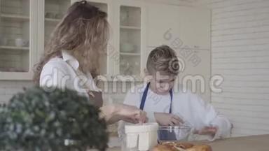 漂亮的女人和她十几岁的儿子在厨房里做蛋糕，那个男孩帮妈妈做食物。 妈妈想弄脏